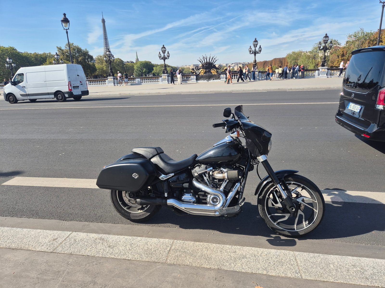 A black Harley-Davidson parked on a Paris bridge with the Eiffel Tower in the background.
