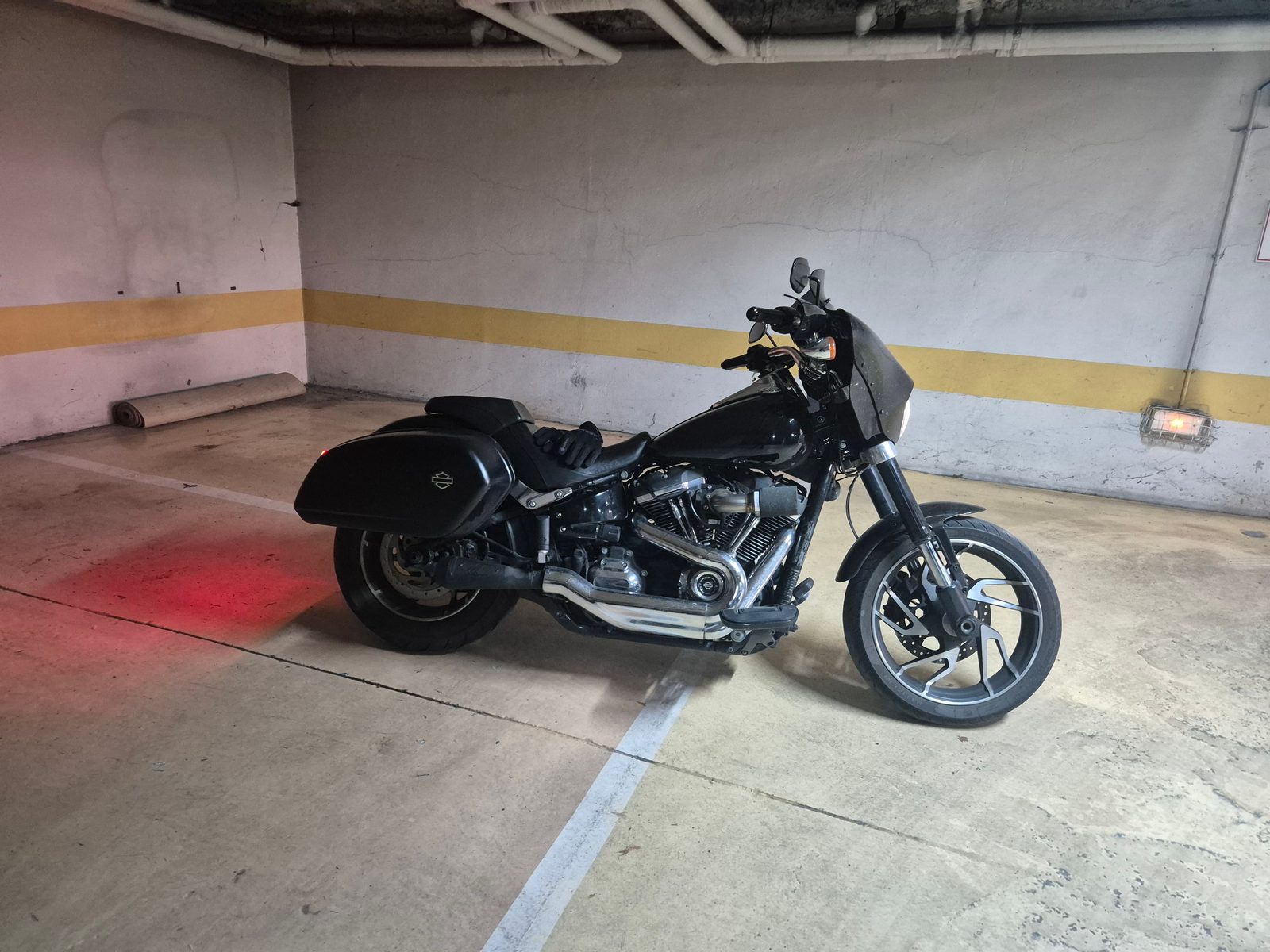 A black Harley-Davidson with panniers and a front fairing parked in an underground car park.